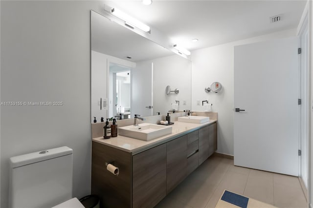 full bath featuring double vanity, tile patterned flooring, visible vents, and a sink