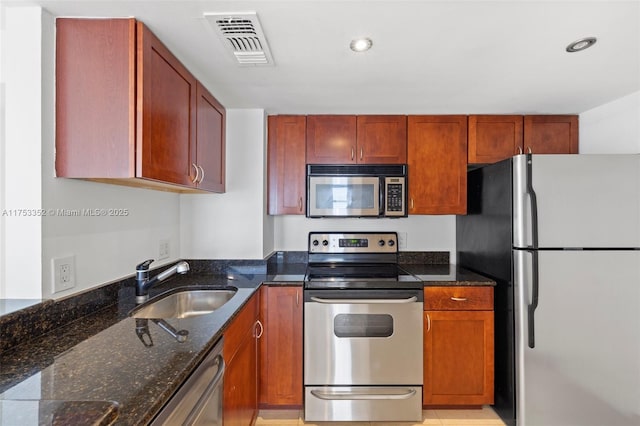 kitchen with appliances with stainless steel finishes, dark stone counters, visible vents, and a sink