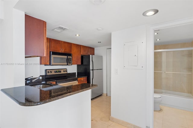 kitchen featuring stainless steel appliances, visible vents, a sink, dark stone countertops, and a peninsula