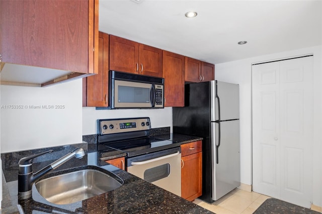 kitchen with light tile patterned floors, dark stone counters, stainless steel appliances, a sink, and recessed lighting