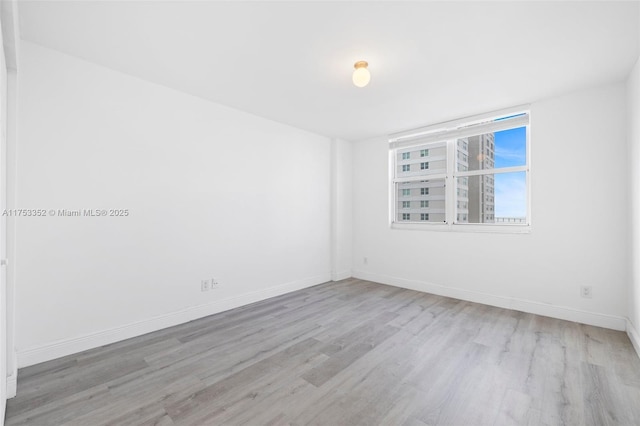 spare room featuring baseboards and wood finished floors