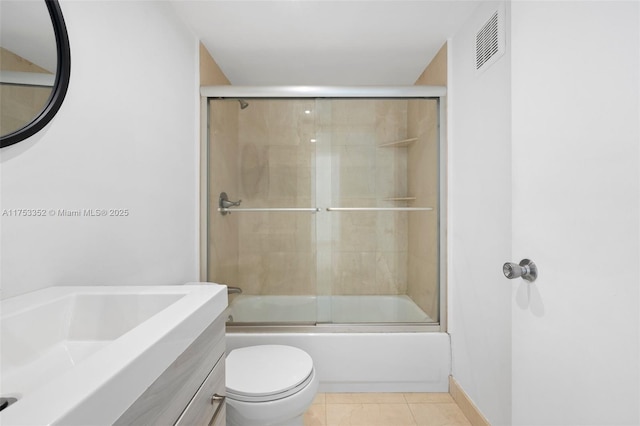 bathroom with visible vents, toilet, shower / bath combination with glass door, tile patterned flooring, and vanity