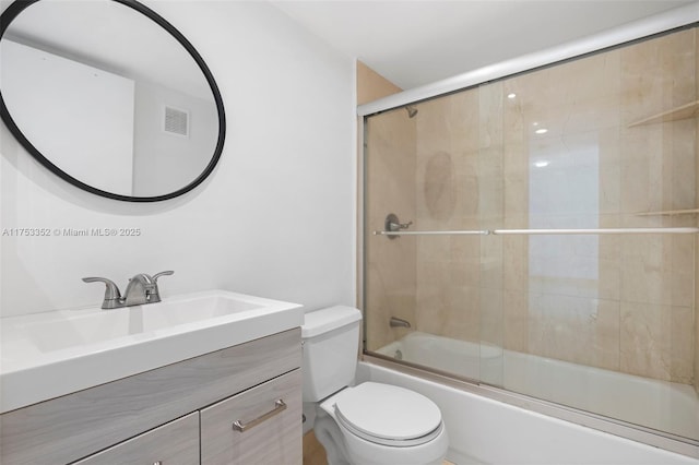 bathroom featuring toilet, visible vents, bath / shower combo with glass door, and vanity