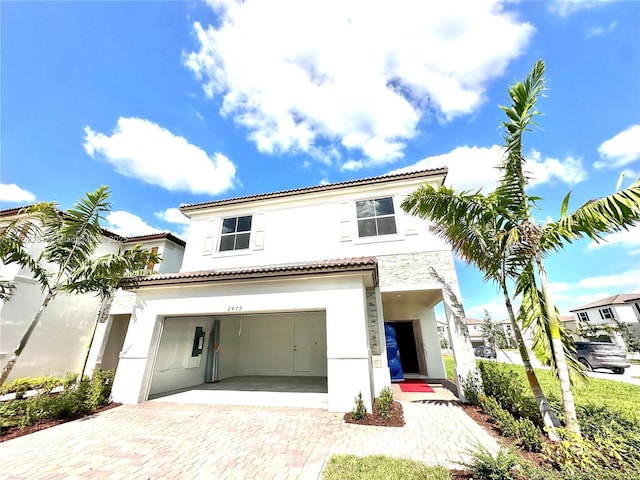 view of front of home featuring decorative driveway, a tiled roof, an attached garage, and stucco siding