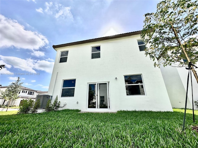 rear view of house with a lawn and stucco siding