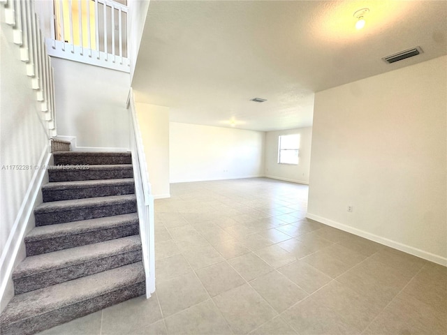 stairs with visible vents, baseboards, and tile patterned floors