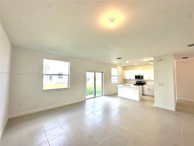 kitchen featuring white cabinetry, open floor plan, light countertops, appliances with stainless steel finishes, and a center island