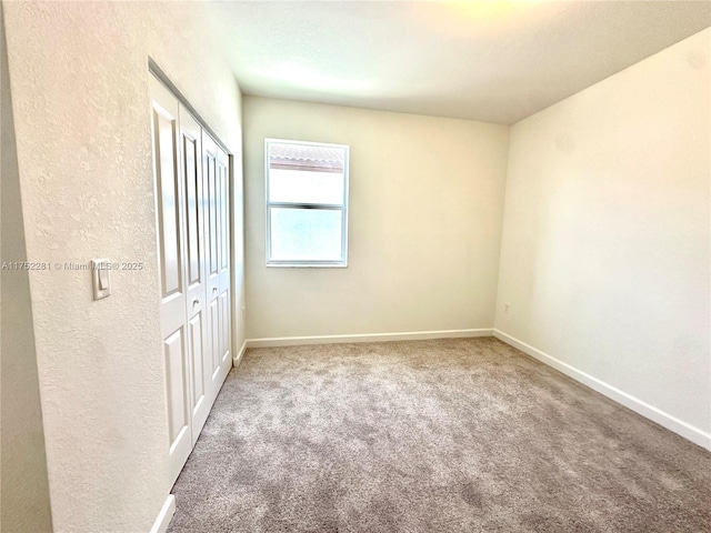 carpeted spare room featuring baseboards