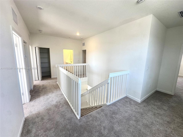 hallway featuring carpet, visible vents, and baseboards