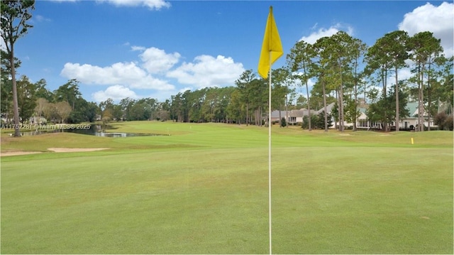 surrounding community with a water view, a lawn, and golf course view