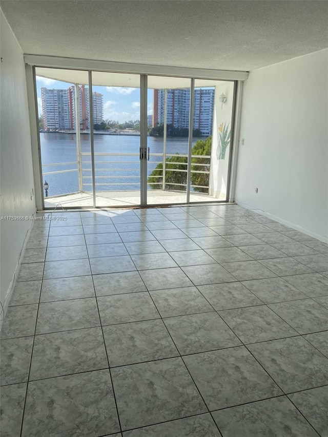 spare room featuring a water view, tile patterned flooring, a view of city, and a textured ceiling