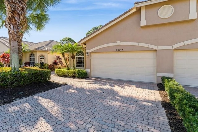 view of front of property featuring a garage, decorative driveway, and stucco siding