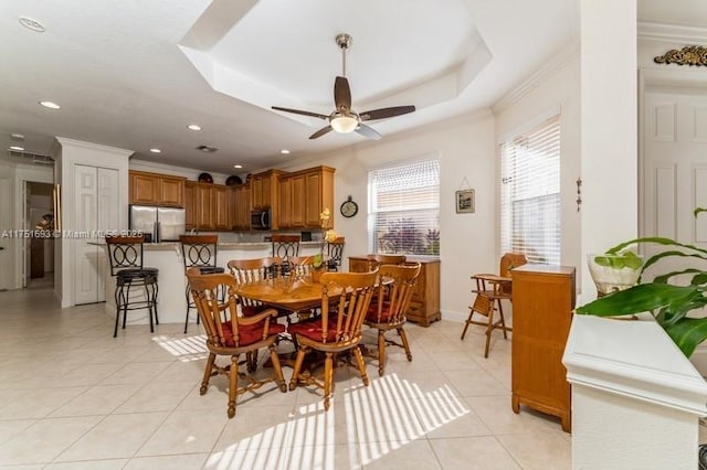 dining space featuring ornamental molding, a raised ceiling, and light tile patterned flooring