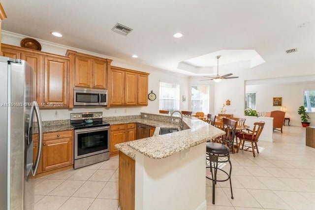 kitchen with visible vents, a peninsula, stainless steel appliances, a kitchen bar, and light tile patterned flooring