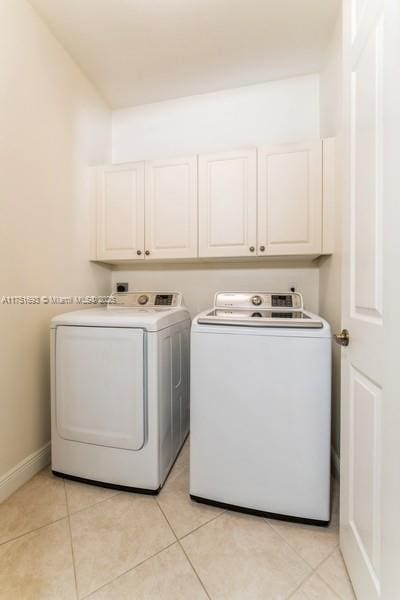 clothes washing area featuring cabinet space, independent washer and dryer, baseboards, and light tile patterned floors