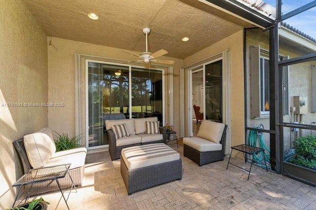 view of patio with glass enclosure, an outdoor living space, and a ceiling fan