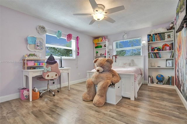 bedroom with a textured ceiling, wood finished floors, and baseboards