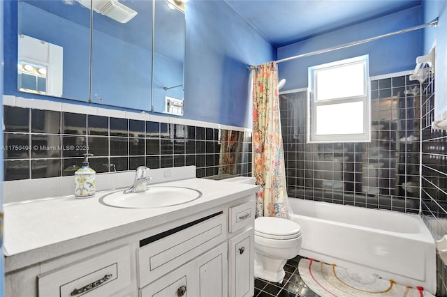 full bathroom with tile walls, shower / bath combination with curtain, toilet, vanity, and tile patterned flooring