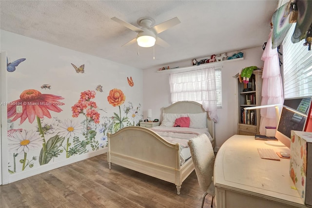 bedroom with a textured ceiling, wood finished floors, a ceiling fan, and baseboards