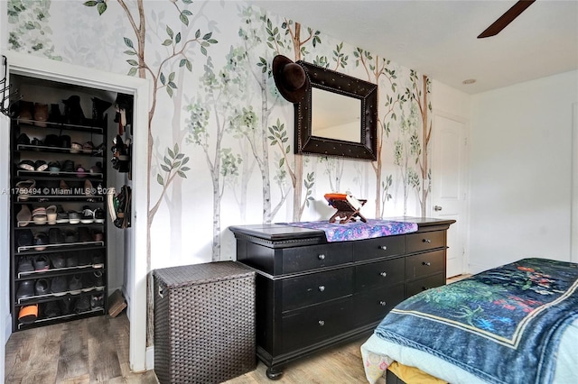 bedroom with light wood-type flooring, wallpapered walls, and a ceiling fan