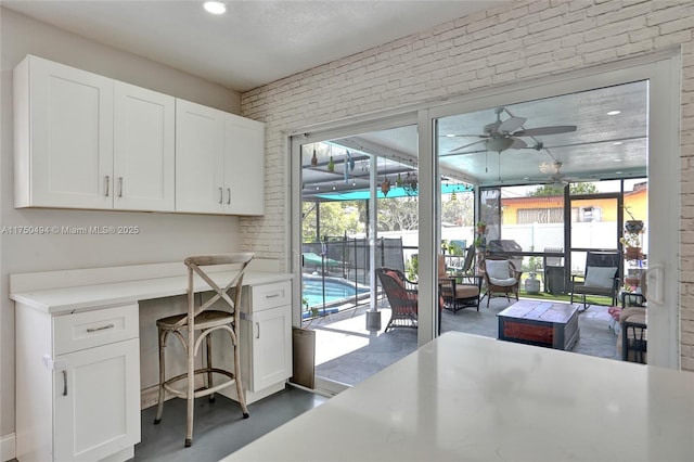 office with plenty of natural light, concrete floors, brick wall, and ceiling fan