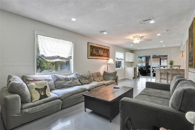 living area with concrete flooring, a textured ceiling, visible vents, and recessed lighting