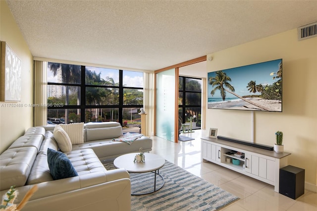 living room featuring a textured ceiling, a wall of windows, light tile patterned flooring, and visible vents