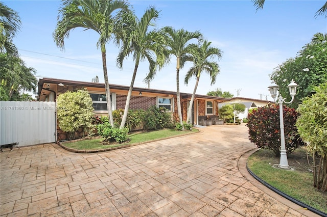 ranch-style home featuring brick siding and fence