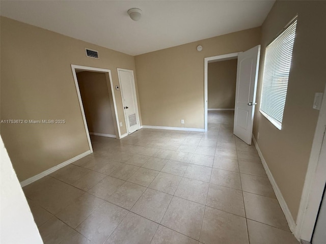 empty room featuring light tile patterned floors, baseboards, and visible vents