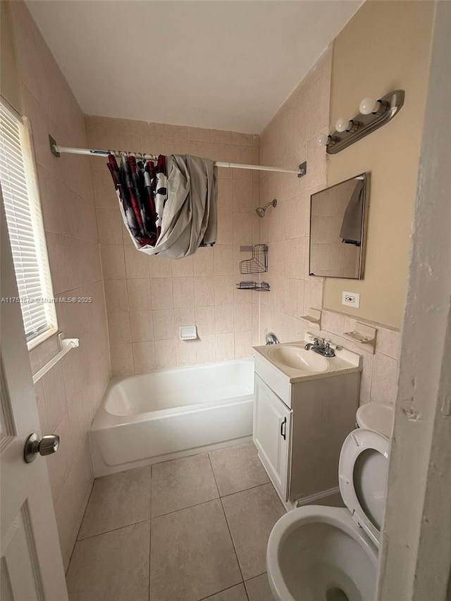 full bath with toilet, tile patterned floors, vanity, washtub / shower combination, and tile walls