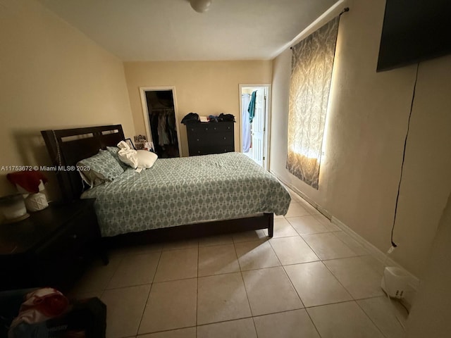 tiled bedroom featuring a spacious closet and a closet