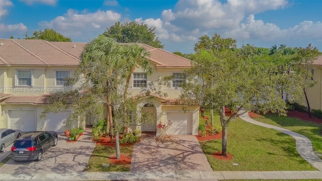 view of front of property with a garage, a tile roof, decorative driveway, and a front yard