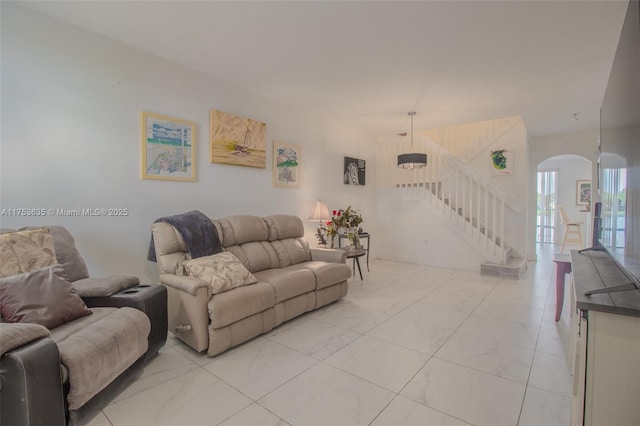 living room featuring marble finish floor, stairway, and arched walkways