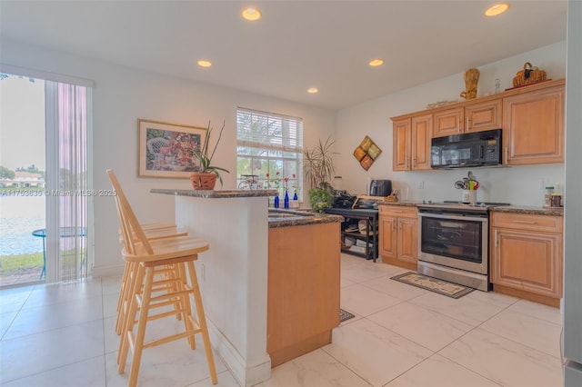 kitchen featuring black microwave, a kitchen island with sink, recessed lighting, a kitchen breakfast bar, and stainless steel electric range oven