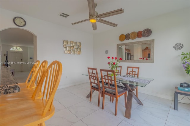 dining space featuring a ceiling fan, arched walkways, visible vents, and baseboards