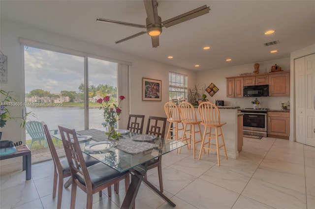 dining room with a water view, ceiling fan, visible vents, and recessed lighting