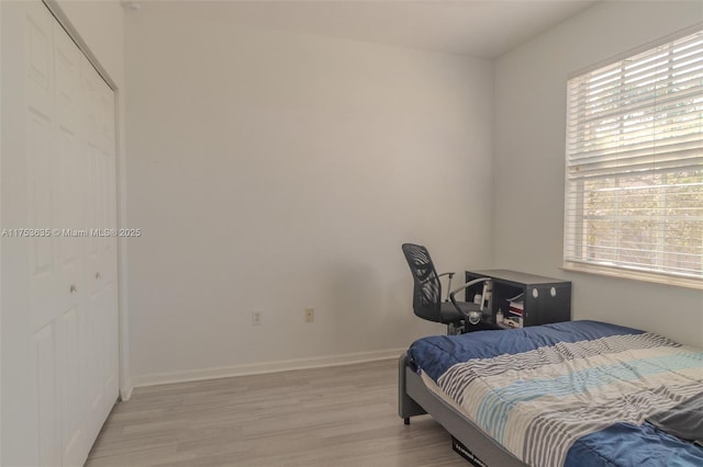 bedroom featuring a closet, light wood-style flooring, and baseboards