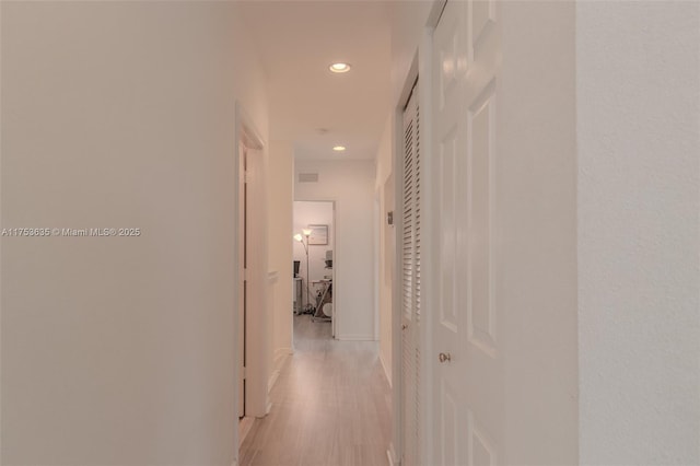 corridor featuring light wood-type flooring, baseboards, and recessed lighting