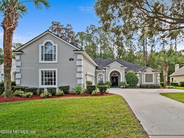 view of front facade with driveway, an attached garage, a front lawn, and stucco siding