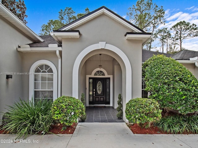 property entrance featuring a shingled roof and stucco siding