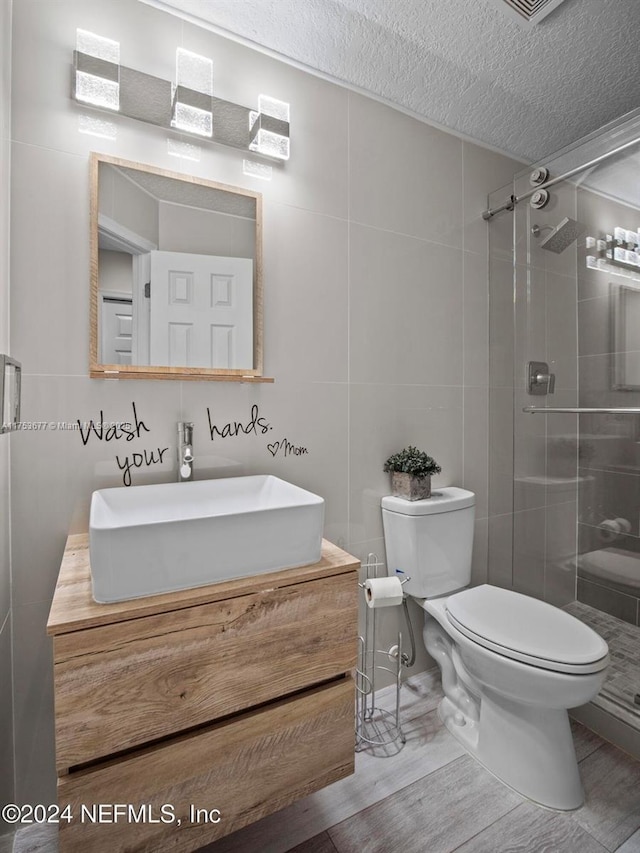 bathroom featuring a stall shower, a textured ceiling, toilet, and vanity