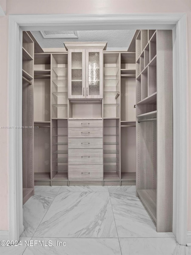 walk in closet with marble finish floor