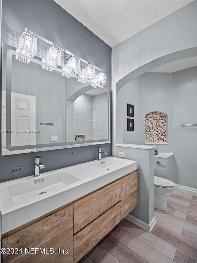 bathroom with wood finished floors, a sink, toilet, and baseboards