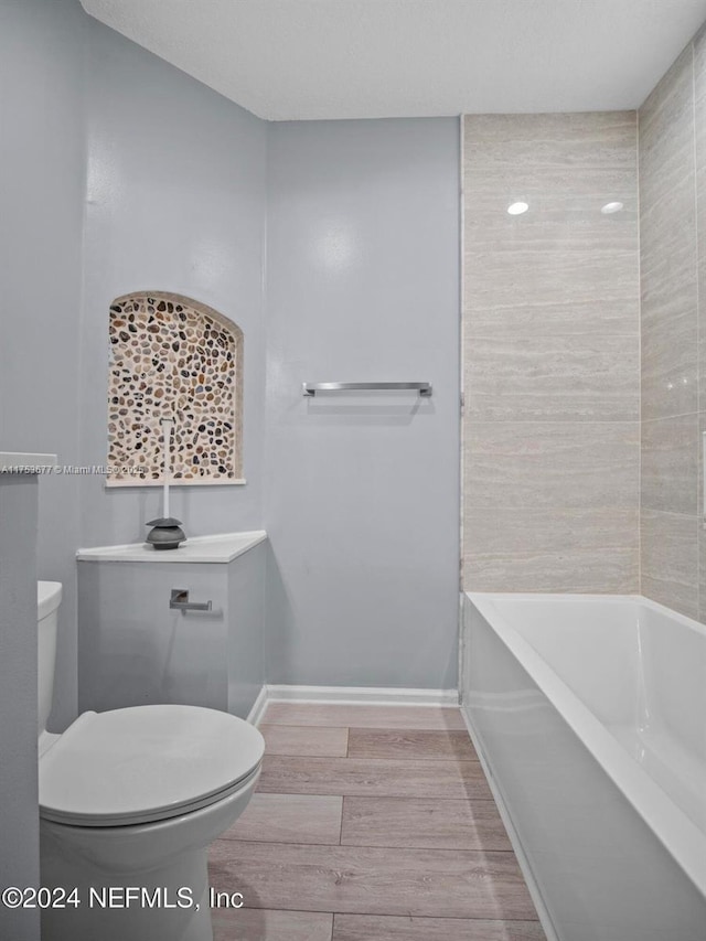 bathroom with baseboards, toilet, and wood finished floors