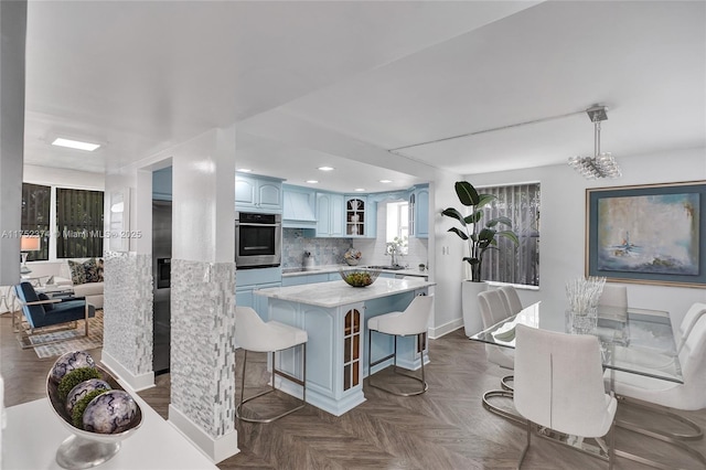 kitchen with tasteful backsplash, a kitchen island, a breakfast bar area, light countertops, and a sink