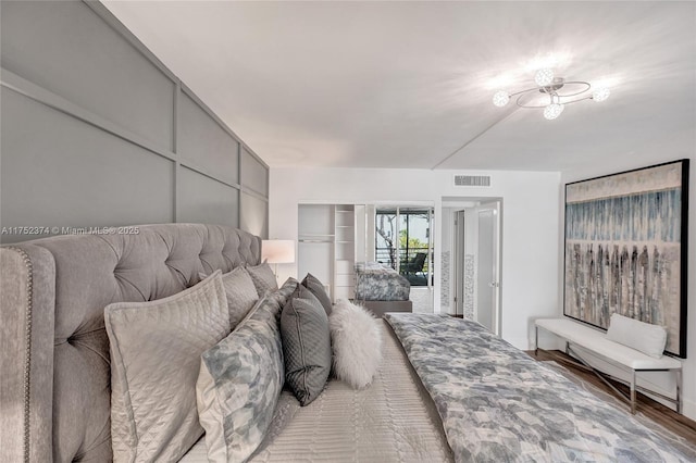 bedroom featuring access to outside, visible vents, and wood finished floors