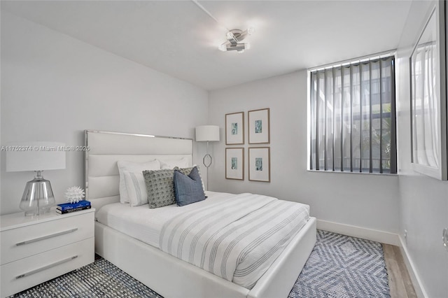 bedroom with multiple windows, baseboards, and wood finished floors