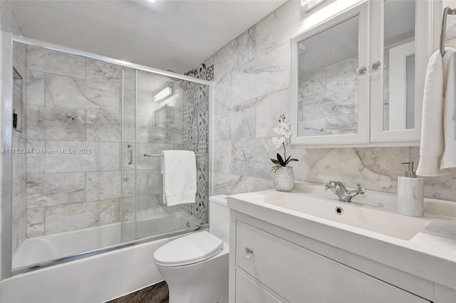 bathroom with shower / bath combination with glass door, tile walls, tasteful backsplash, toilet, and vanity