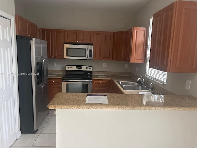 kitchen with stainless steel appliances, light countertops, light tile patterned flooring, a sink, and a peninsula