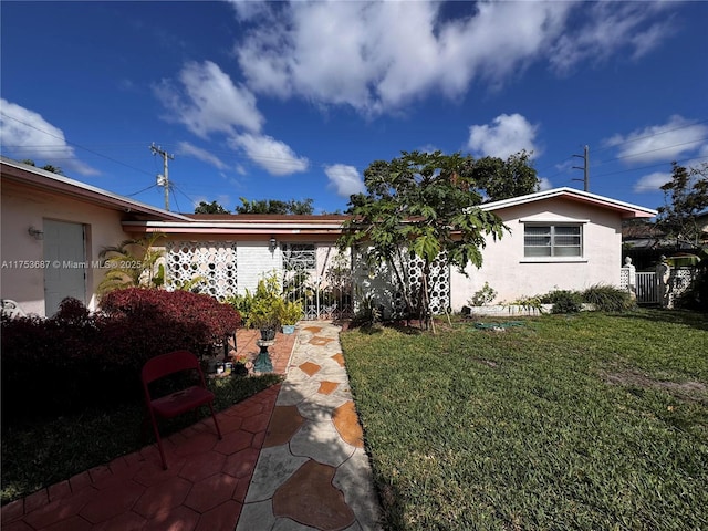 view of front of home with a front lawn, fence, and stucco siding